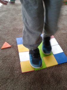 Child jumps on (a now flattened) house made of colorful blocks.