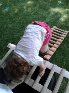 Toddler climbs a variety of ladders while holding on with hands and feet. This is part of an "obstacle course".