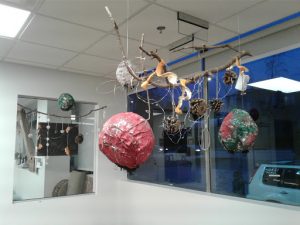 papermache balls are hanging from a branch, hanging in the classroom.